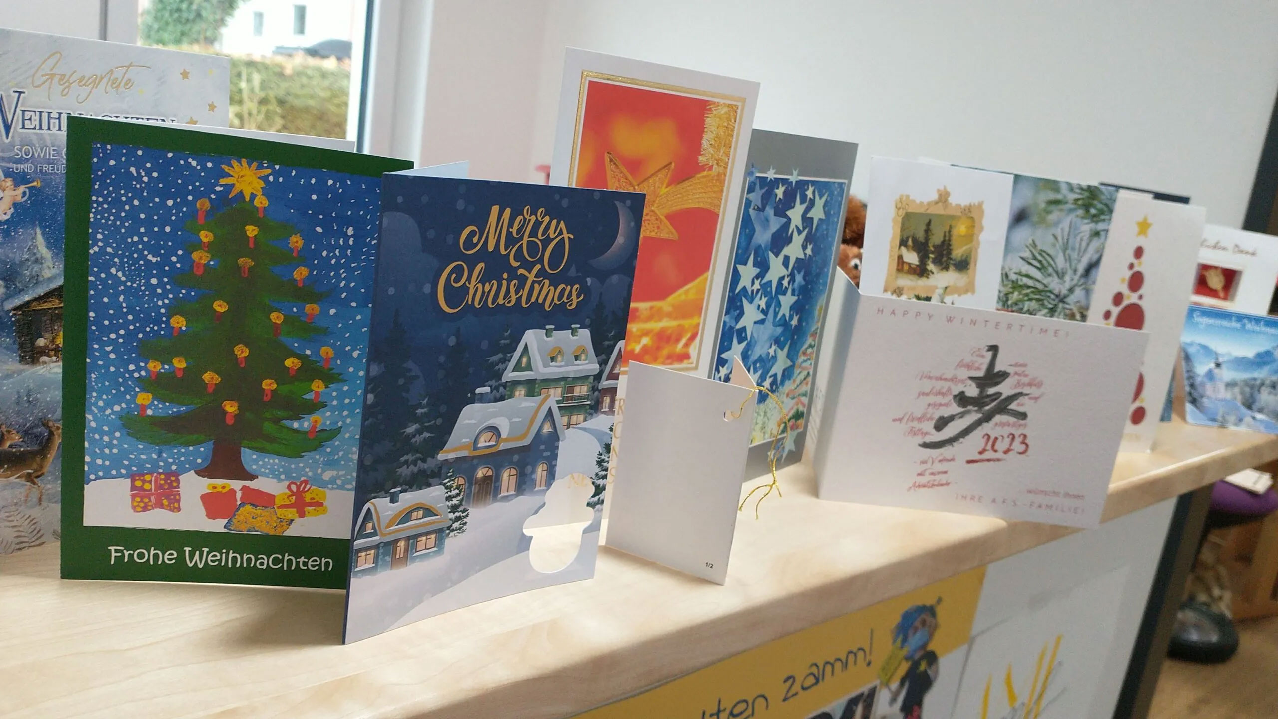 Verschiedene festliche Weihnachtskarten auf einem Tisch, die die herzliche Atmosphäre im Pflegedienst AML zur Weihnachtszeit widerspiegeln und die Wertschätzung gegenüber Patienten und Angehörigen zeigen.