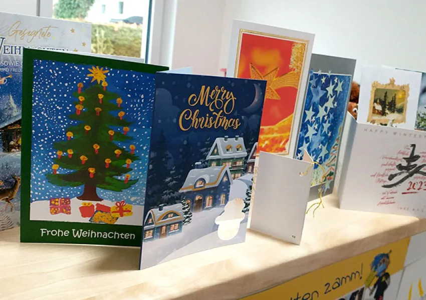 Eine Sammlung von Weihnachtskarten, die nebeneinander auf einem Tisch stehen, repräsentiert die festliche Stimmung und die herzliche Gemeinschaft bei Pflegedienst AML.