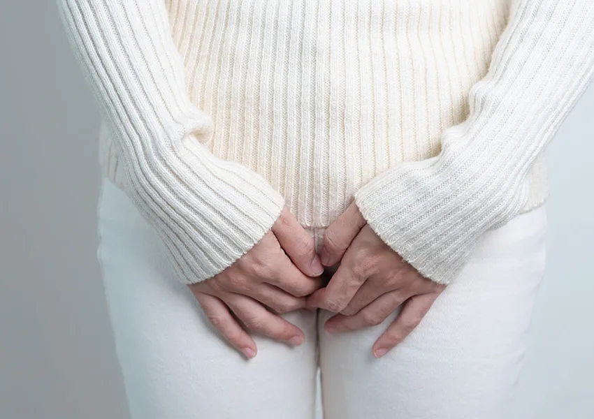 Frau hält sich die Blase - Schwierigkeiten beim Halten vom Urin im Alter