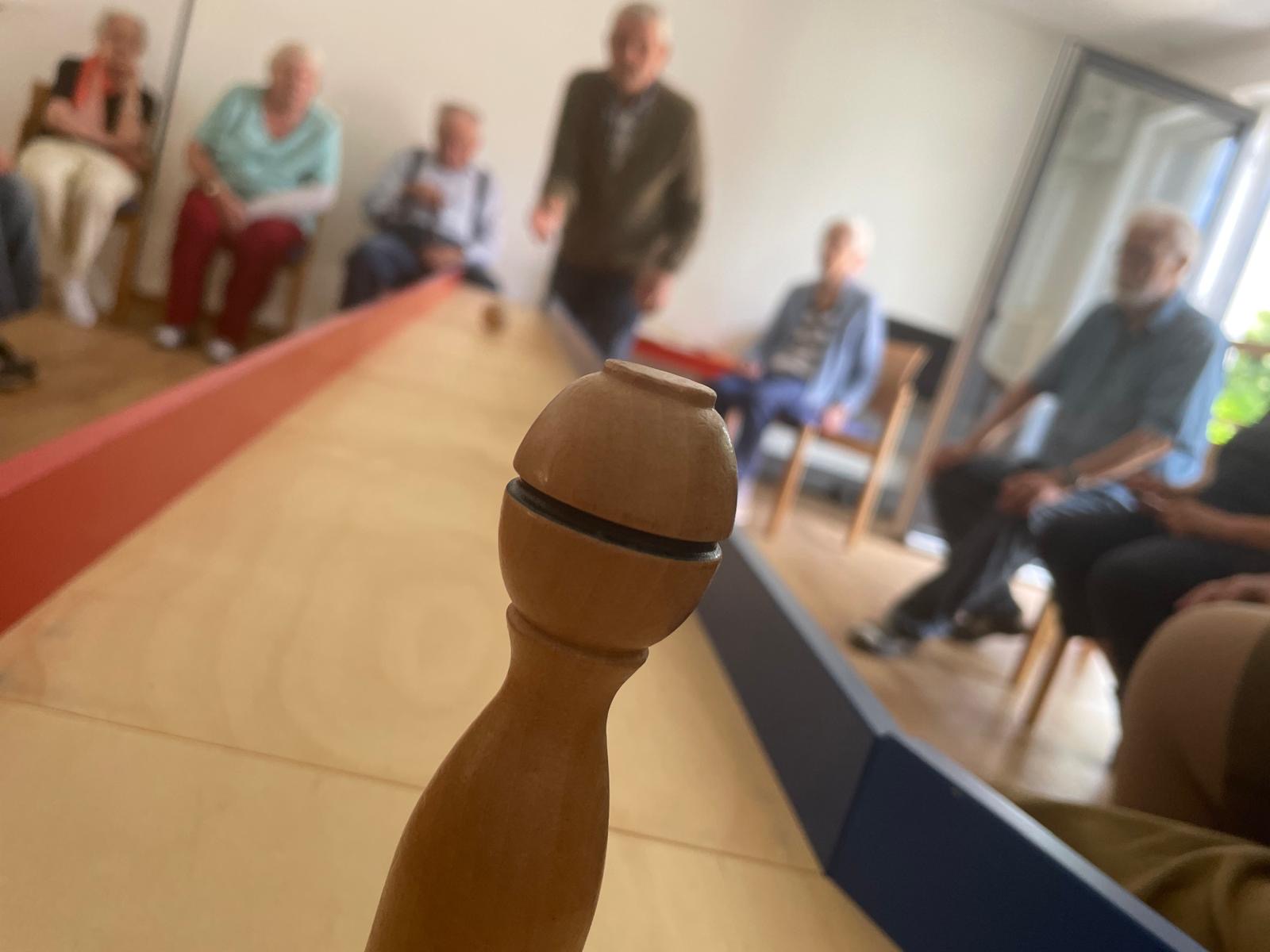 Senioren spielen Kegeln im Sonnencafé, Teil der aktiven Freizeitgestaltung des Pflegedienstes AML.